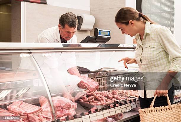 frau kauf von fleisch im the butcher shop - metzgerei stock-fotos und bilder