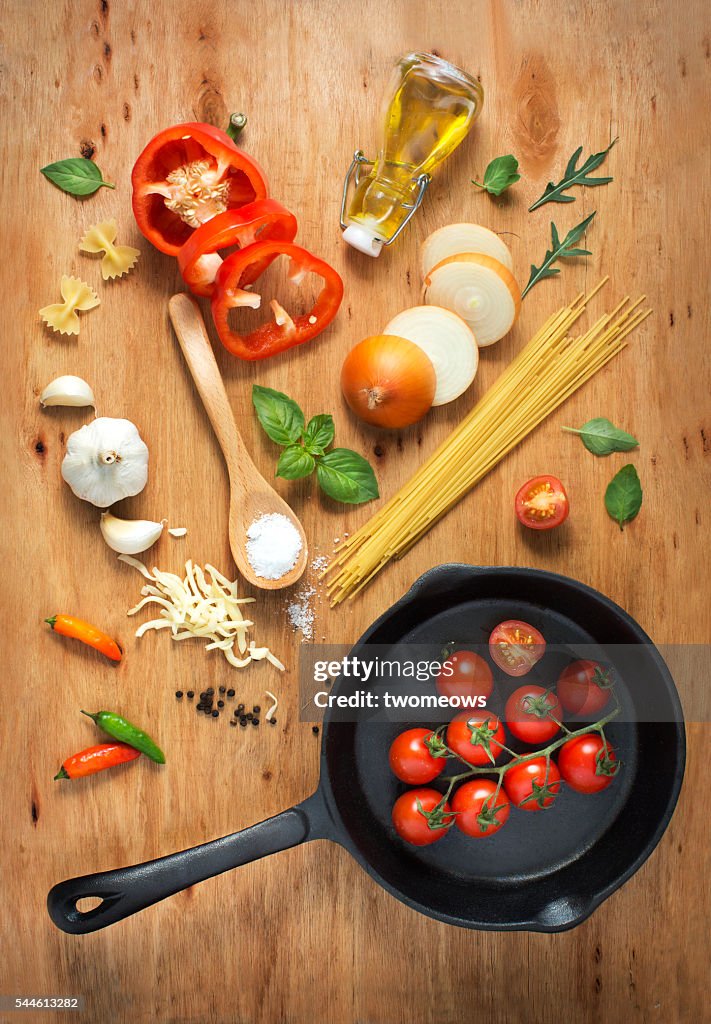 Flat lay cooking pan with freshly cut paste recipe ingredient on rustic wooden table top.
