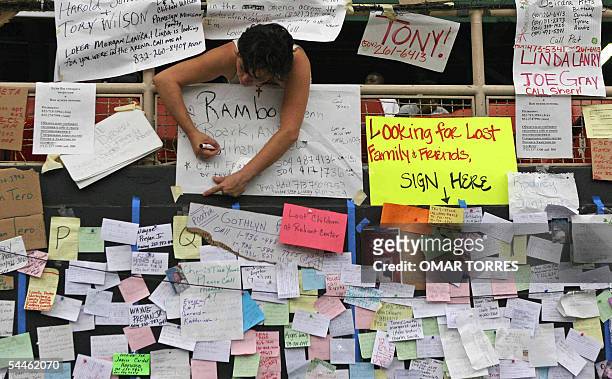 Houston, UNITED STATES: A woman writes a message looking for a relative on a makeshift bulletin board for Hurricane Katrina victims at the Astrodome...