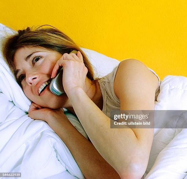 Frau mit Handy im Bett -