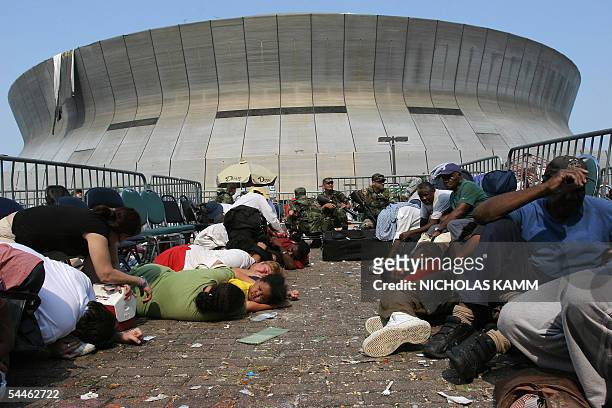 New Orleans, UNITED STATES: People waiting to be evacuated from the Superdome take cover after the National Guard reported shots being fired outide...