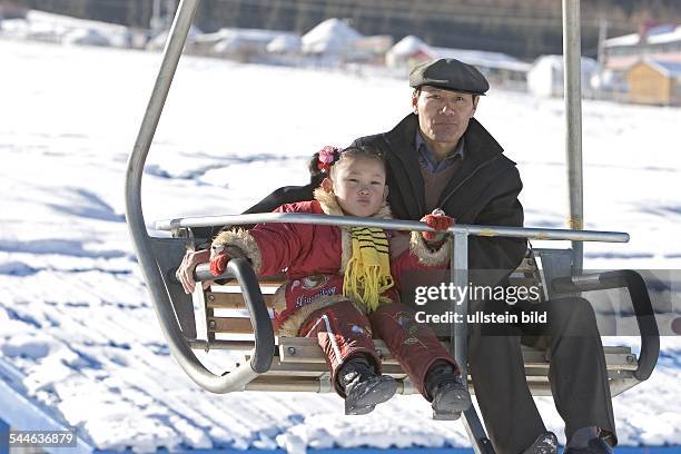 China, Xinjiang, Urumqi - Skigebiet nahe der Stadt Urumqi: Grossvater mit Enkelkind im Sessellift | New ski-region near the city of Urumqi for the...