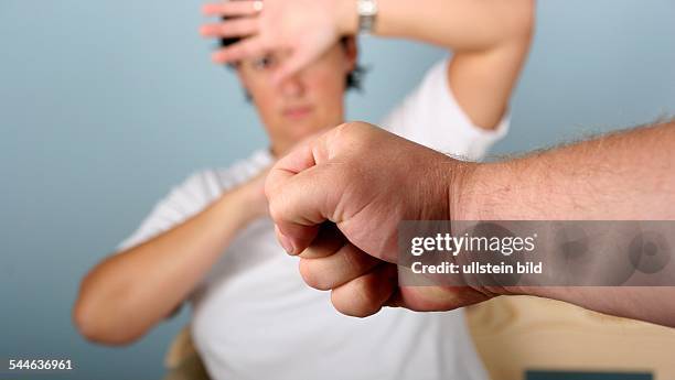 Symbol Gewalt gegen Frauen, Frau schützt sich mit den Händen vor dem Faustschlag eines Angreifers