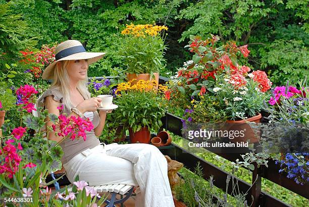 Frau auf Balkon mit Blumen -