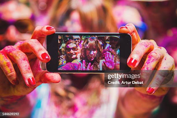 people taking a selfie together in group during a holi celebration party in the outdoor with happiness expressions and covered with vivid colors. - light vivid children senior young focus foto e immagini stock