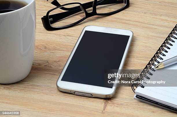 smart phone, coffee, spectacles and notepad with pen - notepad table stockfoto's en -beelden