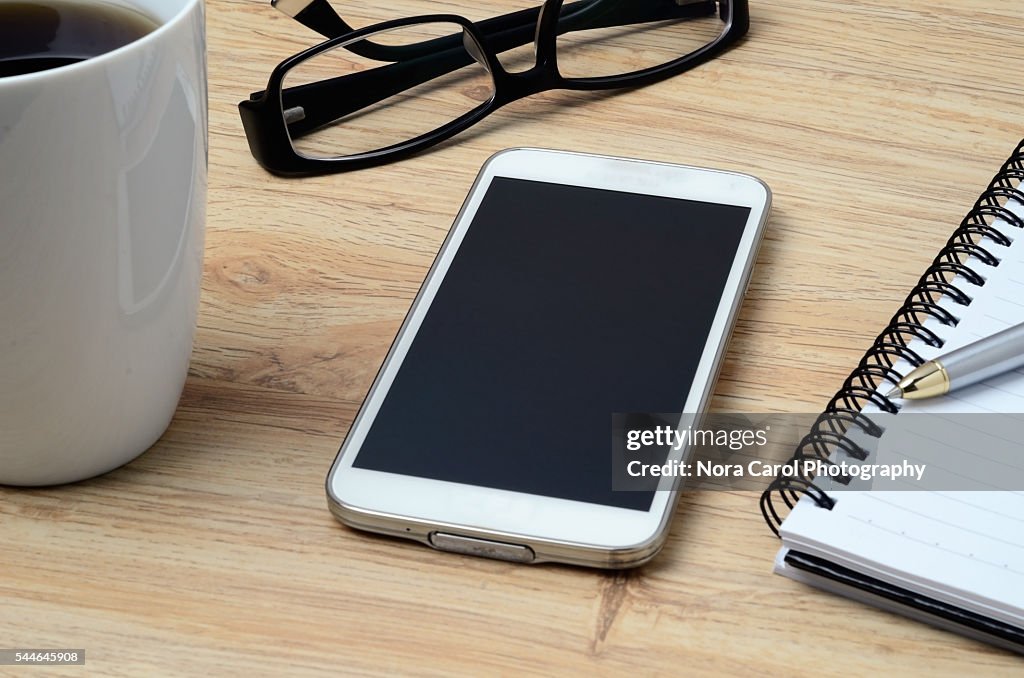 Smart phone, coffee, spectacles and notepad with pen