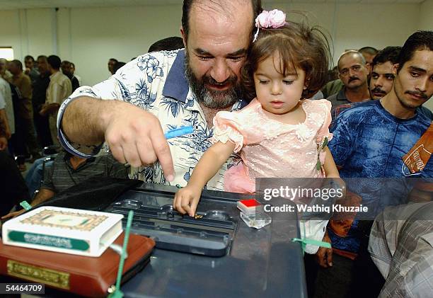 An Iraqi man and his daughter contribute a donation for the families of the Stampede victims at the headquarters of al-Iraqia TV channel, a local TV...