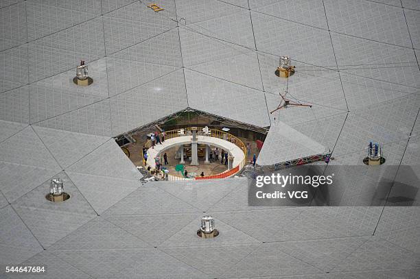 Workers lift the last panel to install into the center of a Five-hundred-meter Aperture Spherical Telescope on July 3 China. The dish-like telescope,...