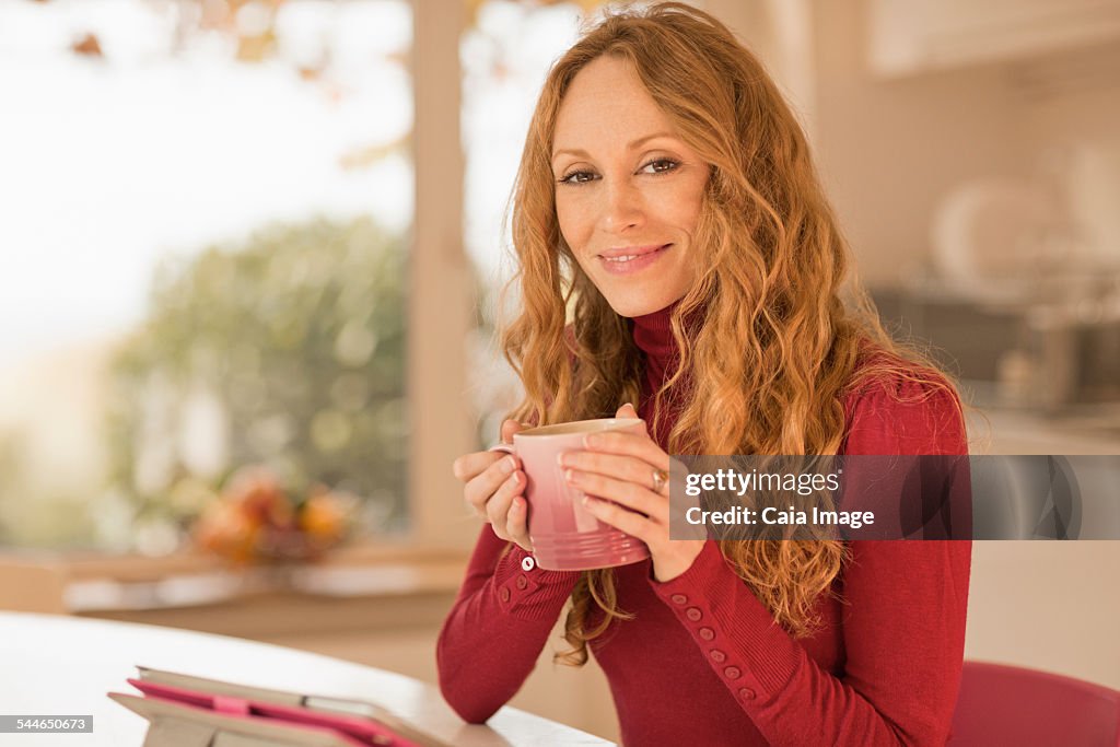Smiling woman drinking coffee in kitchen