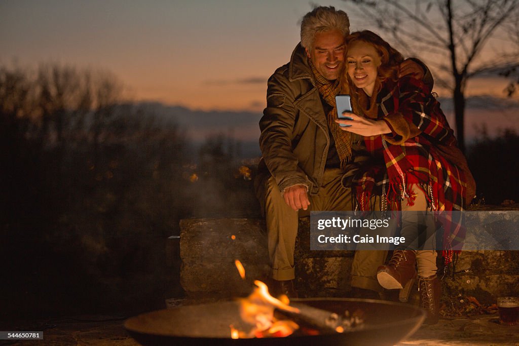 Couple relaxing on patio by fire taking photo