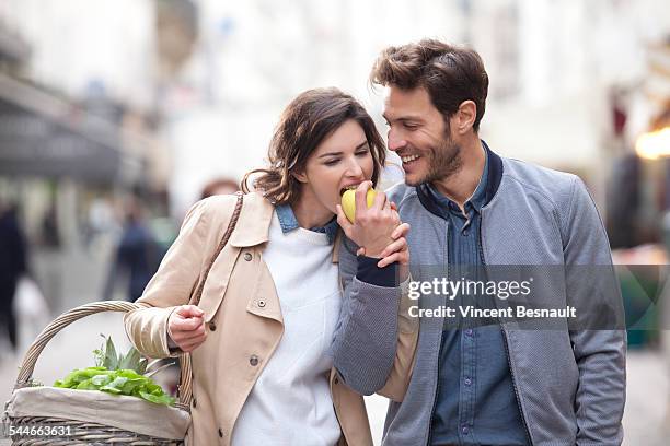 couple eating apple in the street - frau apfel stock-fotos und bilder