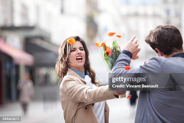 woman hitting a man with a bouquet of flowers - picchiare foto e immagini stock