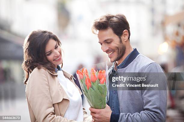 woman offering flowers to a man in the street - woman giving flowers stock-fotos und bilder