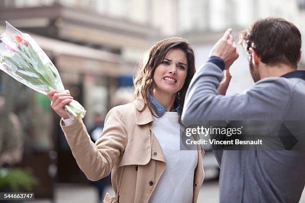 woman hitting a man with a bouquet of flowers - envy stock pictures, royalty-free photos & images