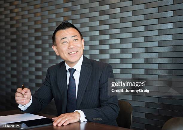 confident japanese businessman making notes, smiling - smug 個照片及圖片�檔