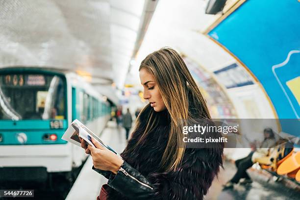 donna leggendo una rivista in stazione della metropolitana di parigi - french culture foto e immagini stock