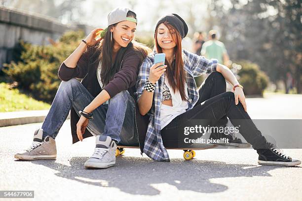 teenage girls with smart phone and skateboard - skating park stock pictures, royalty-free photos & images