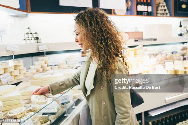 cheerful french woman shopping cheese in a supermarket - paris food stock pictures, royalty-free photos & images