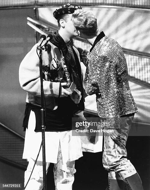 Singer Boy George, of the band Culture Club, kissing Andy Bell, of the band 'Erasure', on stage at the Brit Awards, London, February 15th 1989.