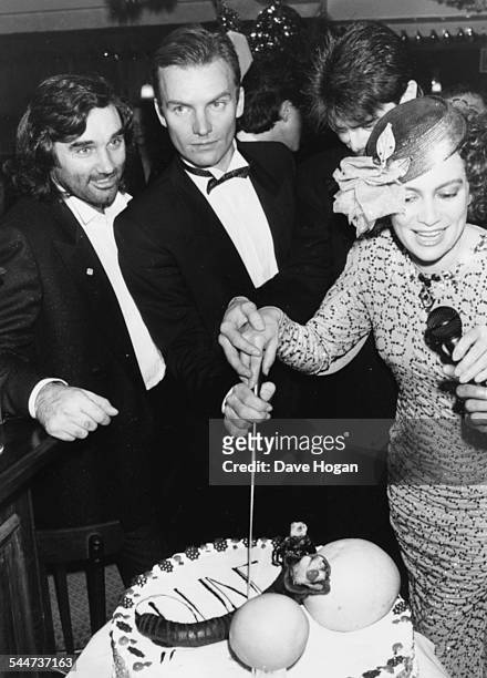 Football player George Best, singer Sting and actress Francesca Annis, cutting a celebration cake at an after party for the film 'Dune', at the club...