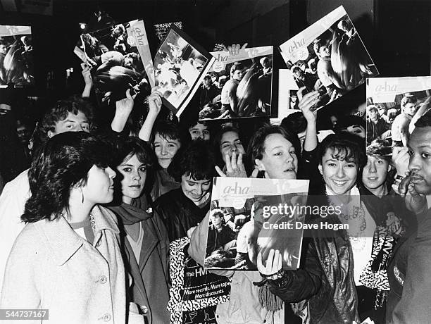 Huge group of young women, fans of the Norweigan pop group 'A-Ha', happily wave their records in the air as they wait outside the HMV store to see...