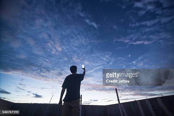 man with phone up to the universe - electronic vapor stock pictures, royalty-free photos & images