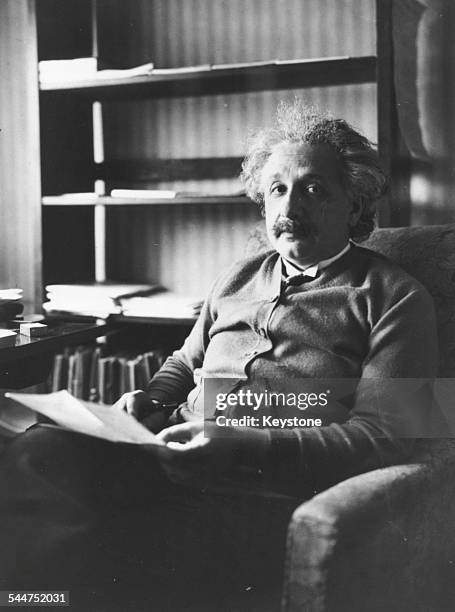 Portrait of physicist Albert Einstein sitting in an armchair and reading, 1929.