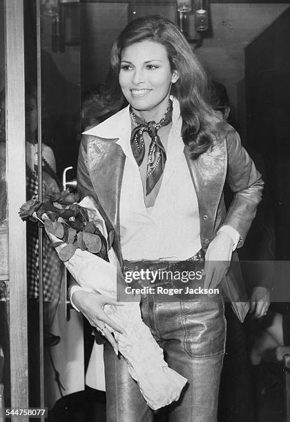 Actress Raquel Welch carrying a bouquet of roses as she leaves the studio after filming an interview for 'On the Ball', London, November 9th 1972.