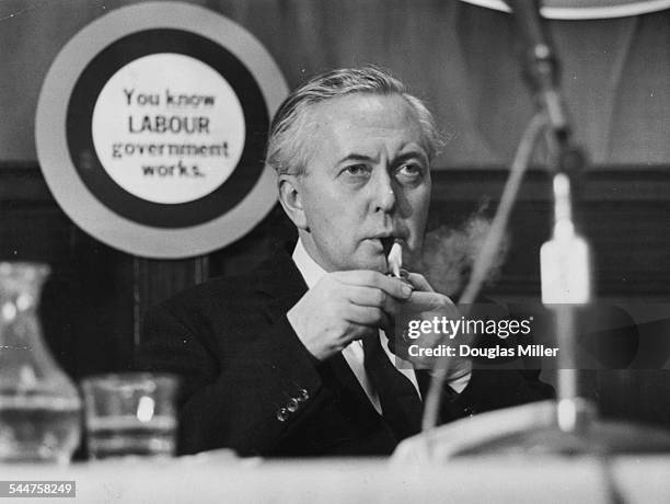 Prime Minister Harold Wilson lighting his pipe while one of his colleagues speaks, at the Labour Party Conference prior to the General Election,...