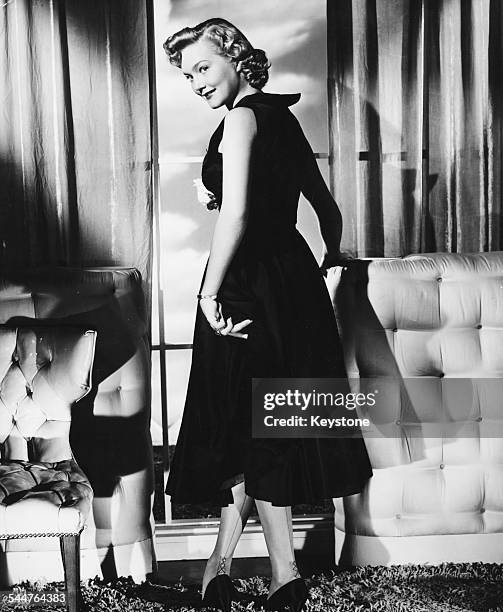 Portrait of actress Patrice Wymore wearing a swing dress and stockings, with her back to the camera, circa 1955.