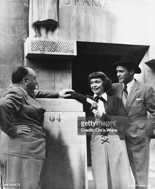 Film director Alfred Hitchcock talking to actors Jane Wyman and Richard Todd, stars of his movie 'Stage Fright', outside the entrance of RADA in...