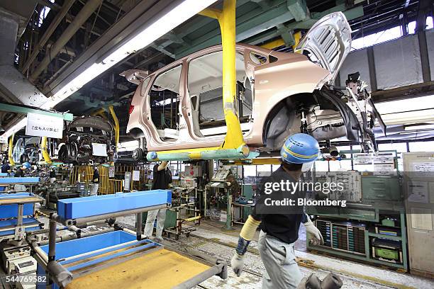 An employee walks past a vehicle on a production line at Mitsubishi Motors Corp.'s Mizushima plant in Kurashiki, Okayama Prefecture, Japan, on...