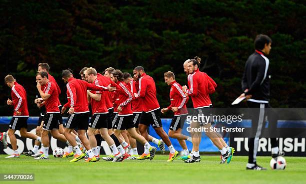 Wales player Gareth Bale and team mates do a warm up run as manager Chris Coleman looks on during Wales training ahead of their UEFA Euro 2016 semi...