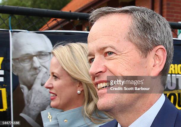 Bill Shorten, Leader of the Opposition and Leader of the Australian Labor Party and his wife Chloe Bryce walk past election posters featuring current...