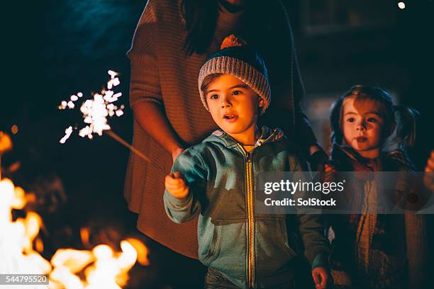 little boy playing with a sparkler - sparkler stock pictures, royalty-free photos & images