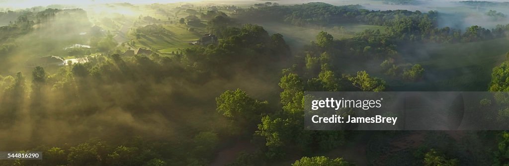 Aerial panorama of foggy valley on edge of town, sunrise