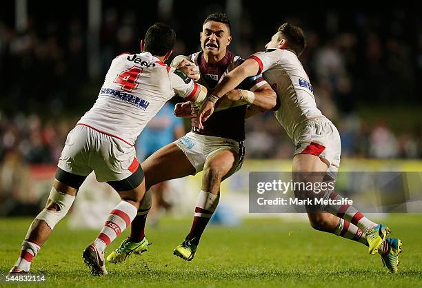 Dylan Walker of the Sea Eagles is tackled by Timoteo Lafai and Gareth Widdop of the Dragons during the round 17 NRL match between the Manly Sea...