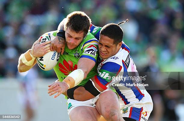 Shaun Fensom of the Raiders is tackled by Sione Mata'utia of the Knights during the round 17 NRL match between the Canberra Raiders and the Newcastle...