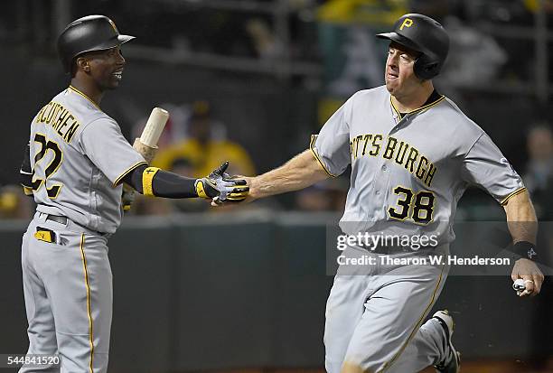 Erik Kratz of the Pittsburgh Pirate is congratulated by Andrew McCutchen after Kratz scored against the Oakland Athletics in the top of the tenth...