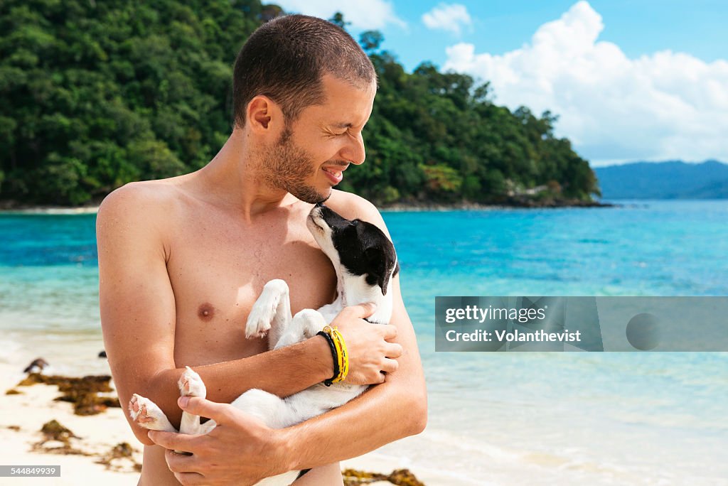Young man playing with dog on the beach