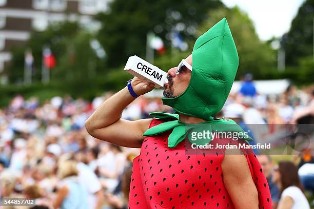 Man dressed as a strawberry drinks cream on Murray mound on day seven of the Wimbledon Lawn Tennis Championships at the All England Lawn Tennis and...