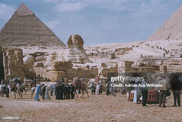 Tourists visit the Giza Necropolis on the outskirts of Cairo, Egypt, circa 1965. From left to right, the Pyramid of Khafre, the Great Sphinx and the...