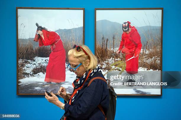 Woman looks at her phone as she visits the exhibition "Yokainoshima" by Charles Freger as part of the photography festival "Rencontres de la...