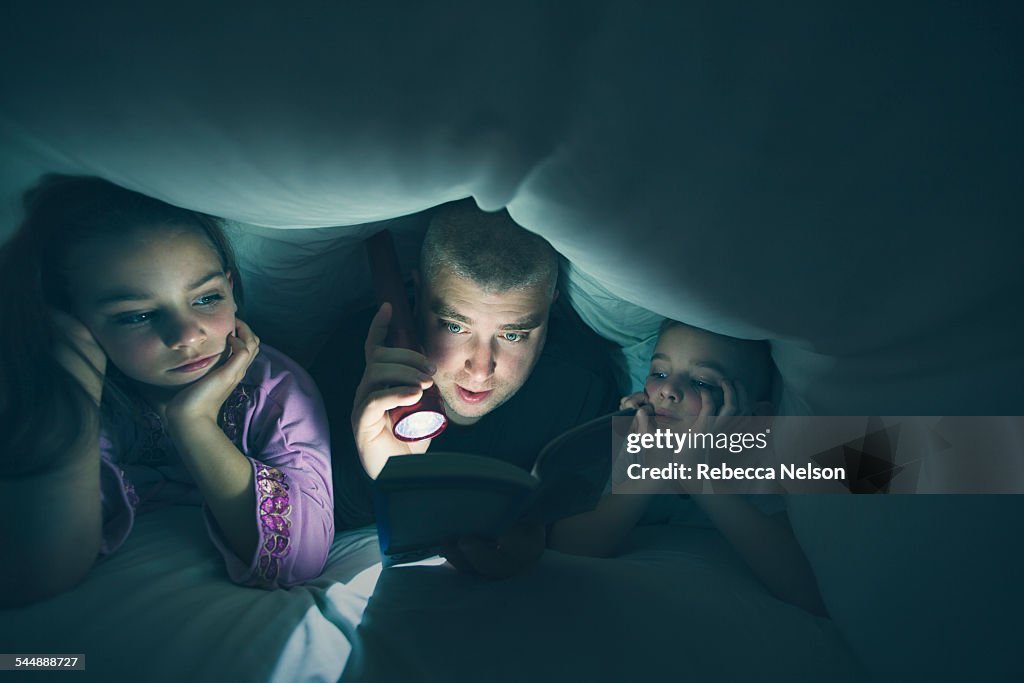 Father reading bedtime story to his children