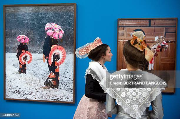 Women wearing a traditional outfit visit the exhibition "Yokainoshima" by Charles Freger as part of the photography festival "Rencontres de la...