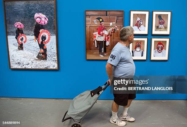 Man, pushing his shopping trolley, visits the exhibition "Yokainoshima" by Charles Freger as part of the photography festival "Rencontres de la...