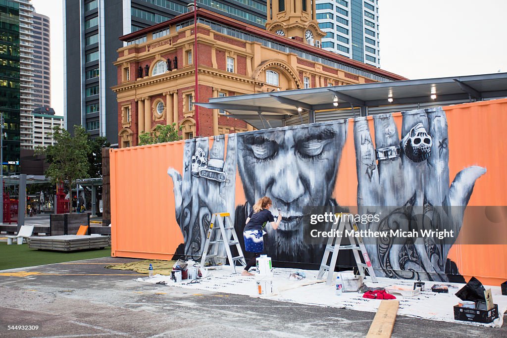An artist creats a mural on a boxcar.