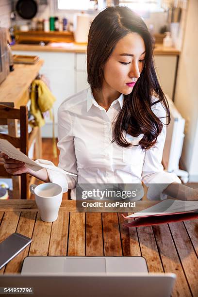 asian woman working at home on contracts and mails - korea apartment woman stock pictures, royalty-free photos & images