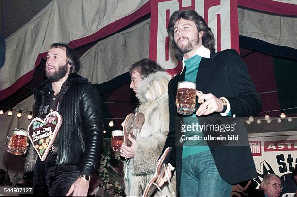 Bee Gees - Band, Pop music, UK/Australia - From left: Maurice, Robin and Barry Gibb at a fun fair in Hamburg drinking beer - 09.1983